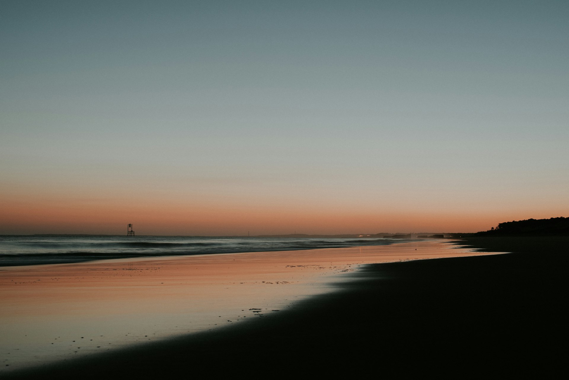 A person walking on a beach at sunset